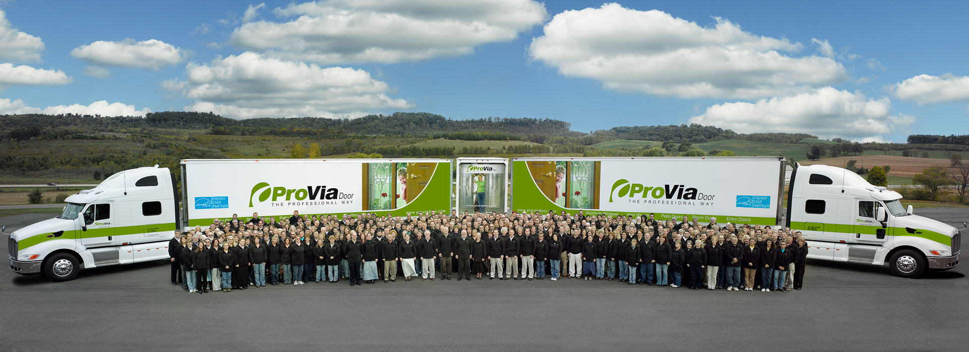 A group photo of ProVia employees in 2007 standing in front of two ProVia semi trucks