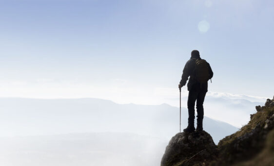 {Stock photo of a person standing on a mountain overlooking the surrounding scenery}