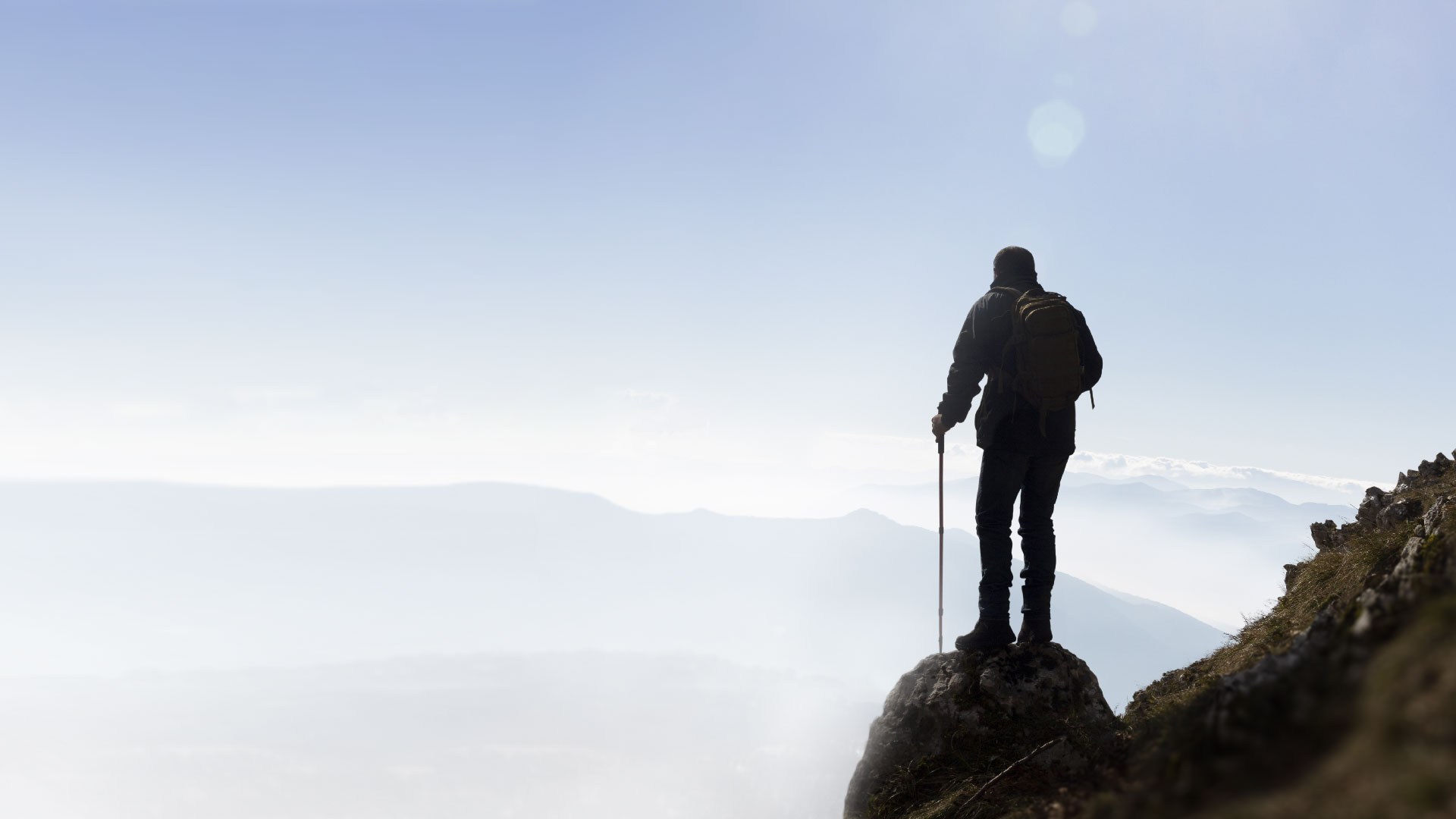 Stock photo of a person standing on a mountain overlooking the surrounding scenery