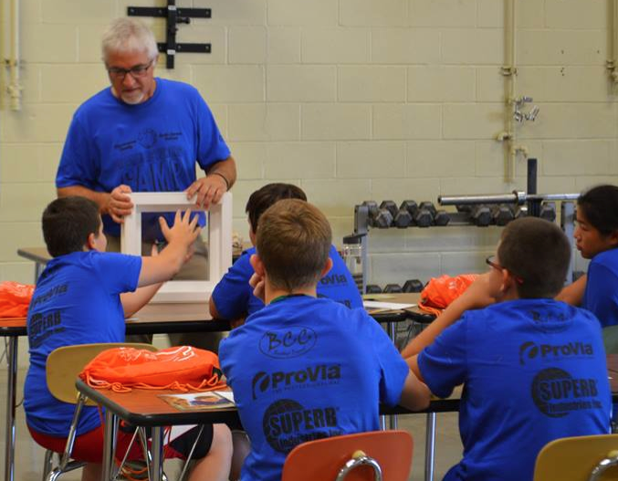 {Group of students in blue t-shirts in a classroom at the first annual 2016 Tuscarawas County Dale Foland Manufacturing Camp, sponsored by ProVia}