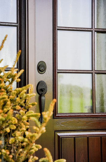 Closeup image of a Signet® Cherry 449-1PP Entry Door with attractive yellow foliage next to it