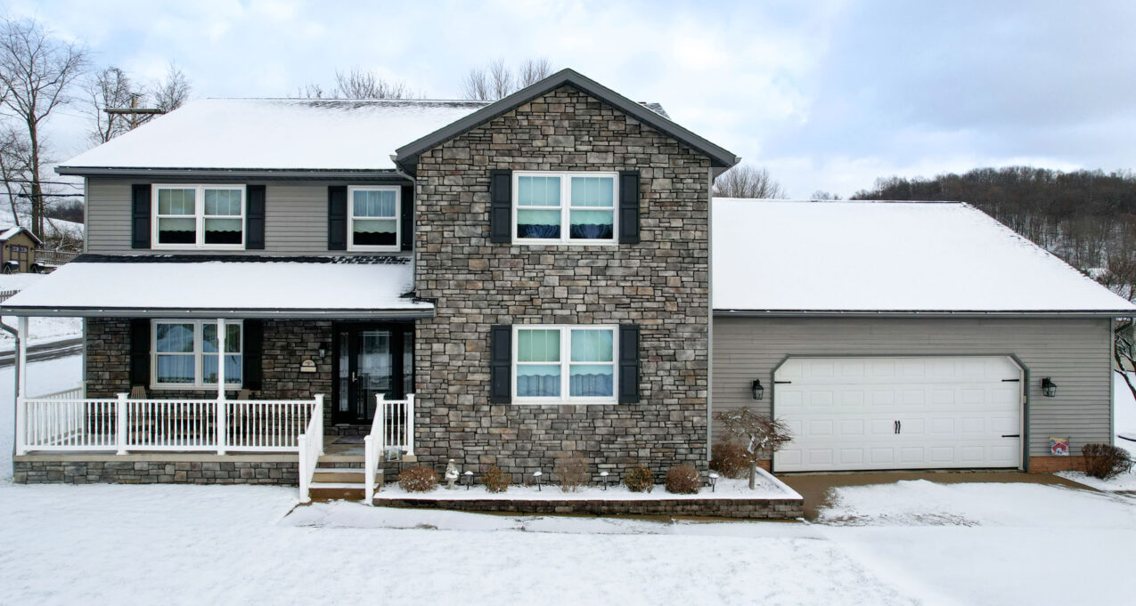 Exterior image of a snow-covered two-story home with ProVia® Aeris™ Double Hung Windows in White with Colonial Internal Grids