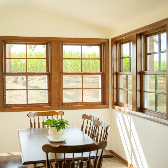 {Interior dining room view of ProVia® Aeris™ Double Hung Windows in Caramel with Cottage Grids}