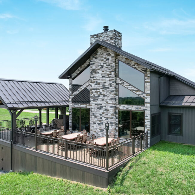 {Home exterior featuring ProVia® CedarMAX® Board and Batten in Timberline with Terra Cut™ Niagara Manufactured Stone}