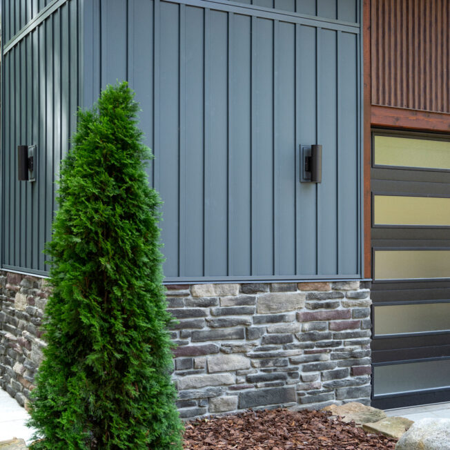 {Closeup home exterior image showing ProVia CedarMax® Board and Batten in Sea Slate with Ledgestone Saginaw Manufactured Stone}