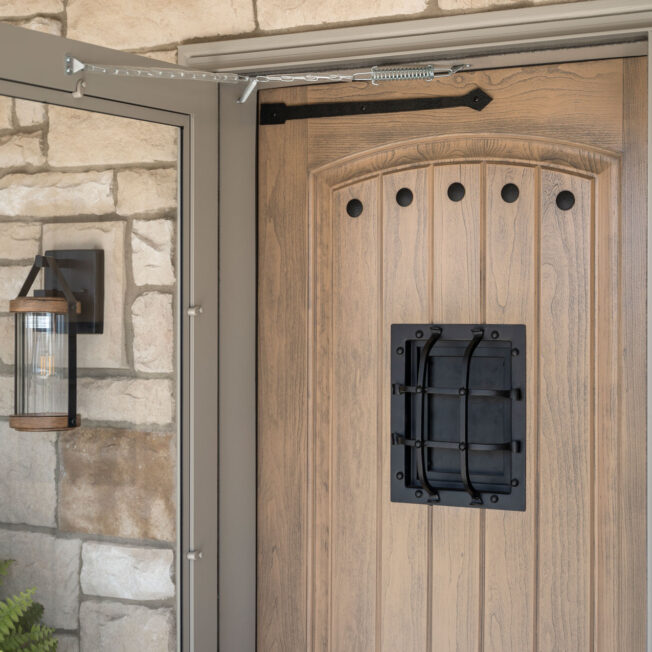 {Closeup exterior view of a ProVia® Signet® Cherry 002CP-449 entry door in Driftwood with Speak Easy, Hinge Strap, and Clavos}