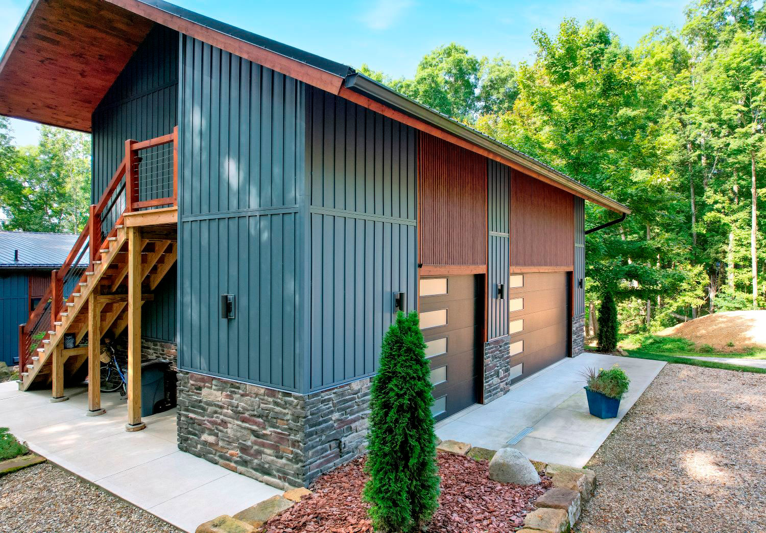 ProVia CedarMAX® Board and Batten vertical siding in Sea Slate on a home combined with wood accents and stone.