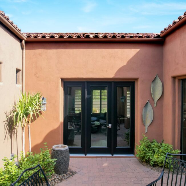 Exterior view of a ProVia® Legacy™ Smooth 460 8-foot front door with 160 sidelites in Coal Black on a Spanish home exterior style