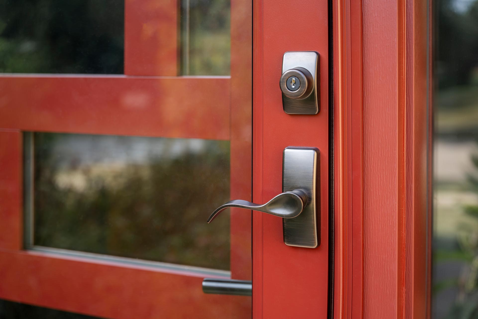 Contemporary Curve Storm Door Hardware in Antique Brass on a ProVia® red storm door