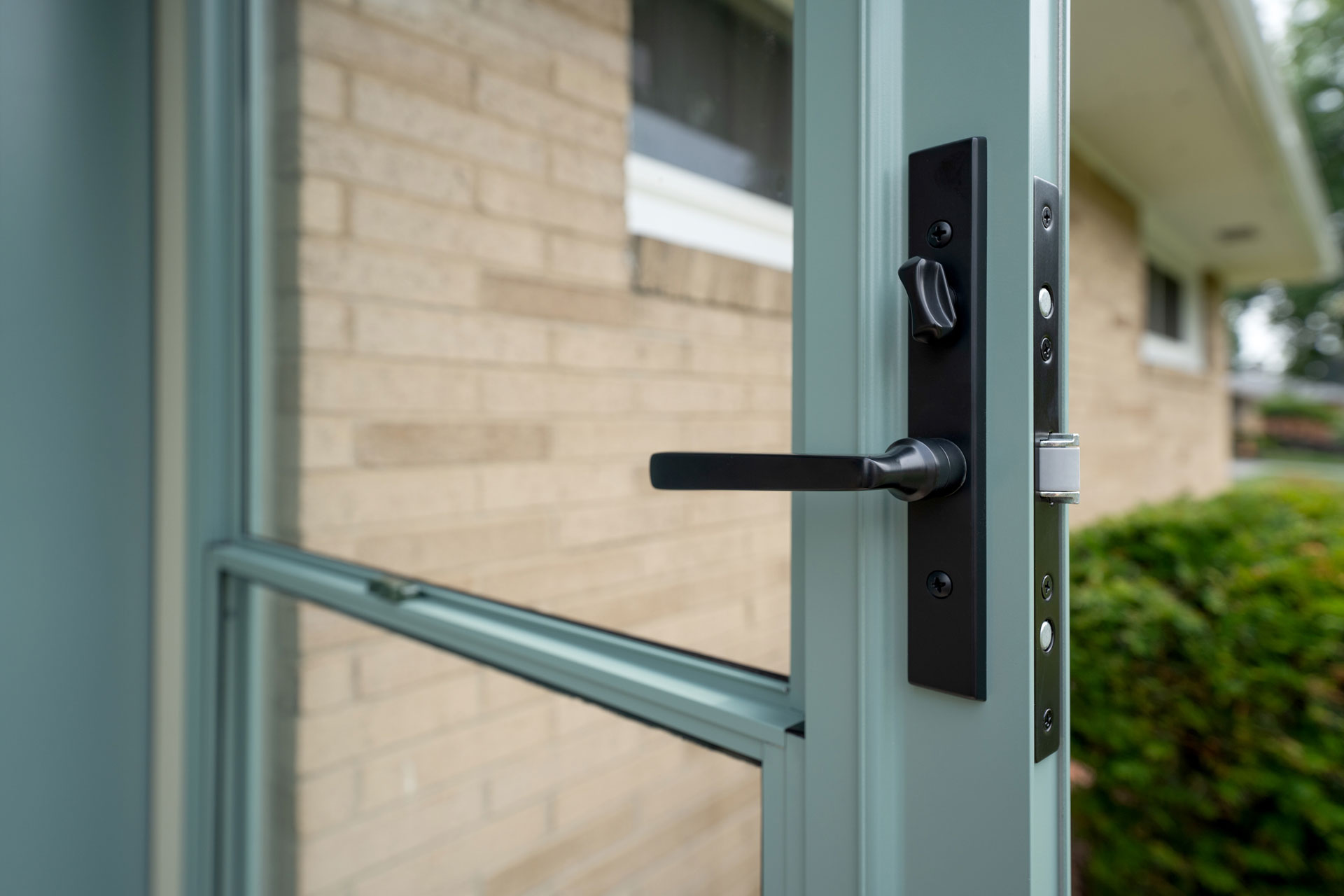 Closeup of Mortise Camden Storm Door Hardware in Black on a Eucalyptus green ProVia® storm door