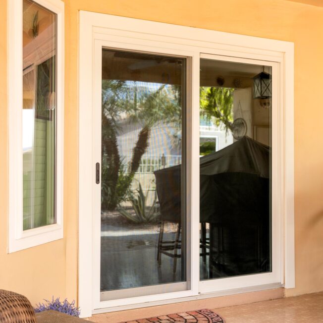 Exterior view of a ProVia® Endure™ 2-Lite Sliding Patio Door and Picture Window in White on a Spanish-style home with a stucco exterior
