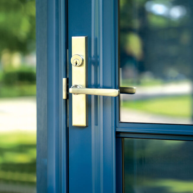 Closeup image of Camden Mortise Multi-Point Storm Door Hardware in Satin Brass on a ProVia® storm door in the color Deep Waters