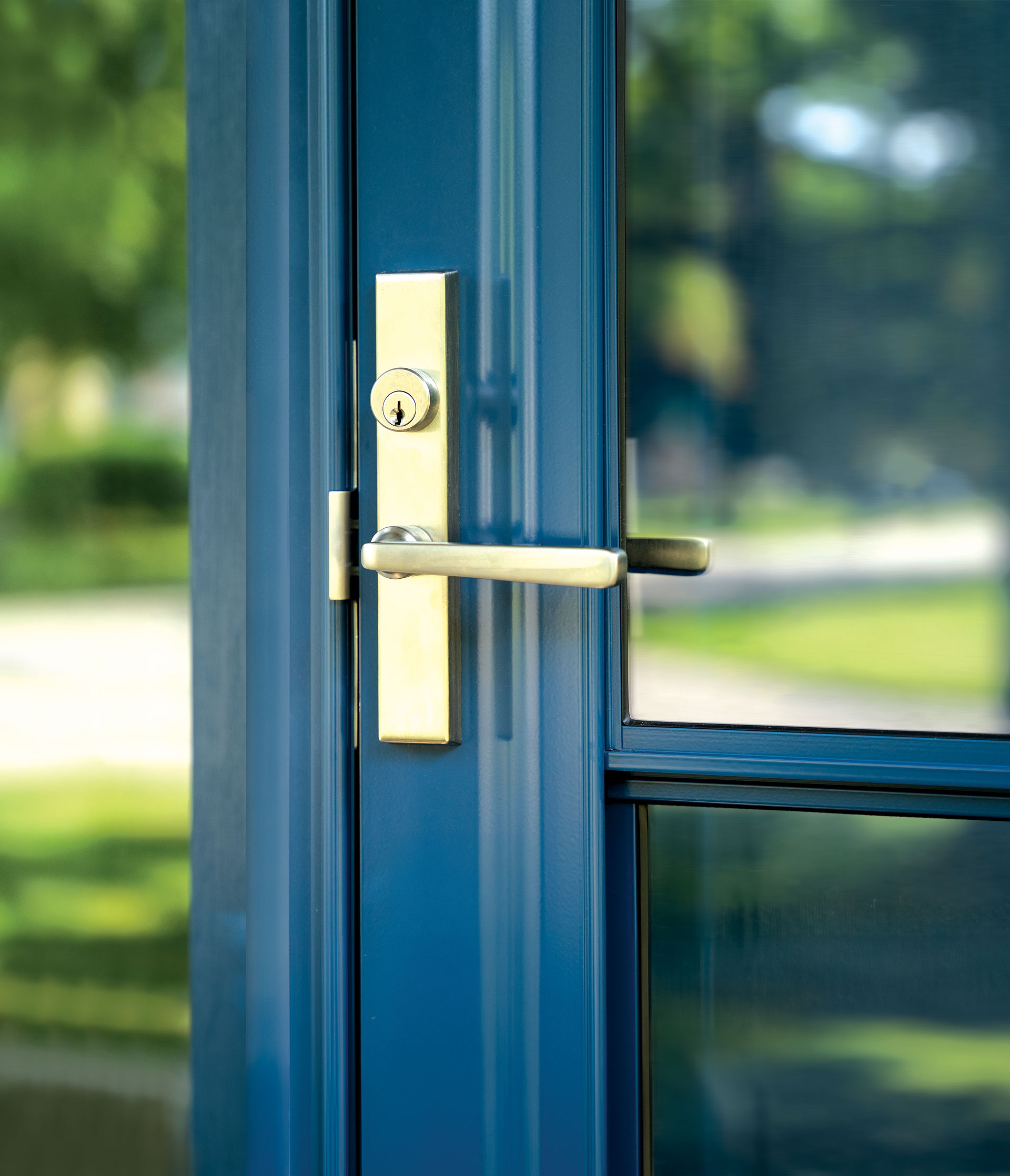 Closeup image of Camden Mortise Multi-Point Storm Door Hardware in Satin Brass on a ProVia® storm door in the color Deep Waters
