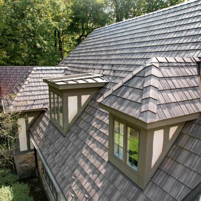 Aerial view of a home with dormer windows and a roof featuring ProVia® Briarwood Shake metal roofing
