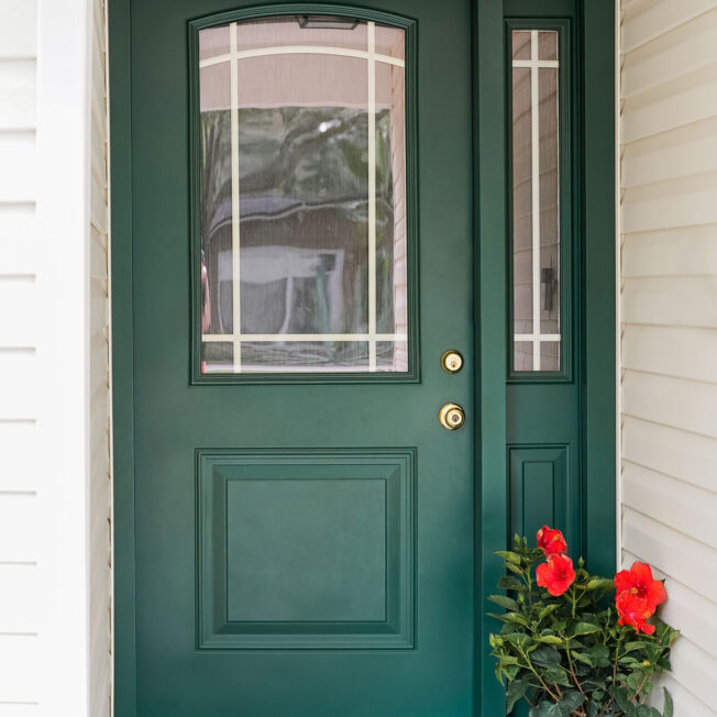 Exterior view of a ProVia® Legacy™ Smooth Steel 437-1P Entry Door in Forest Green with Internal Grids on a front porch