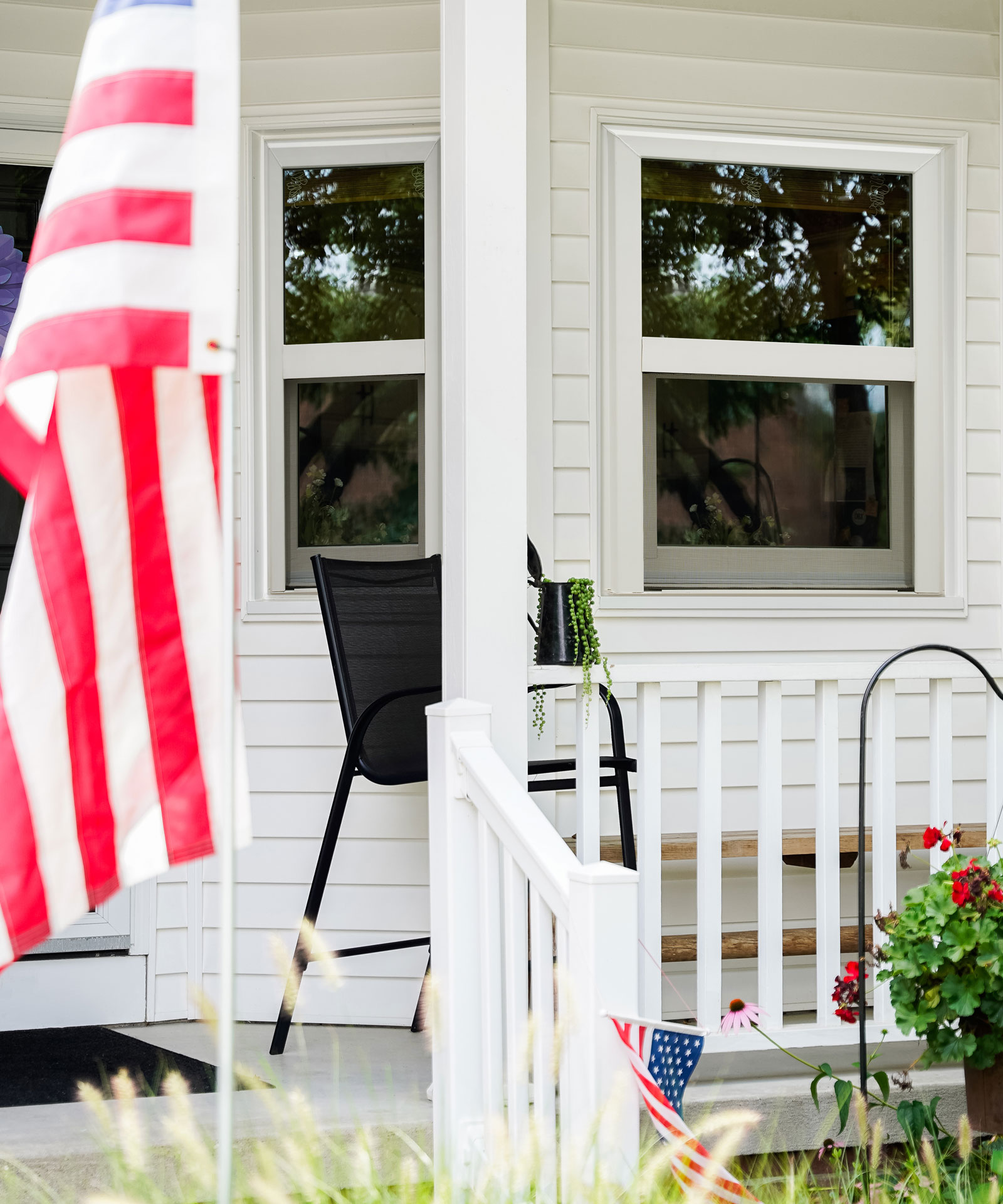 Exterior view of a white home with a porch and ProVia® Endure™ Single Hung Windows in White