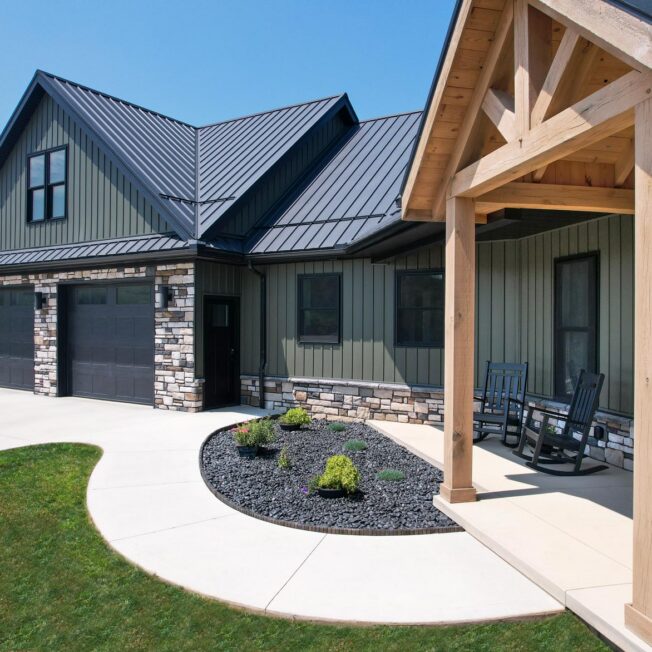 Exterior view of the front of a home featuring ProVia® CedarMAX® Board and Batten in a dark green color Pine