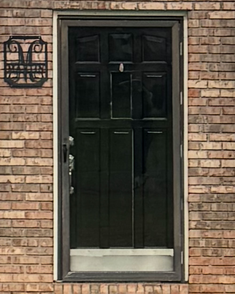 Exterior view of the front of a home with an older black entry door before getting a new door
