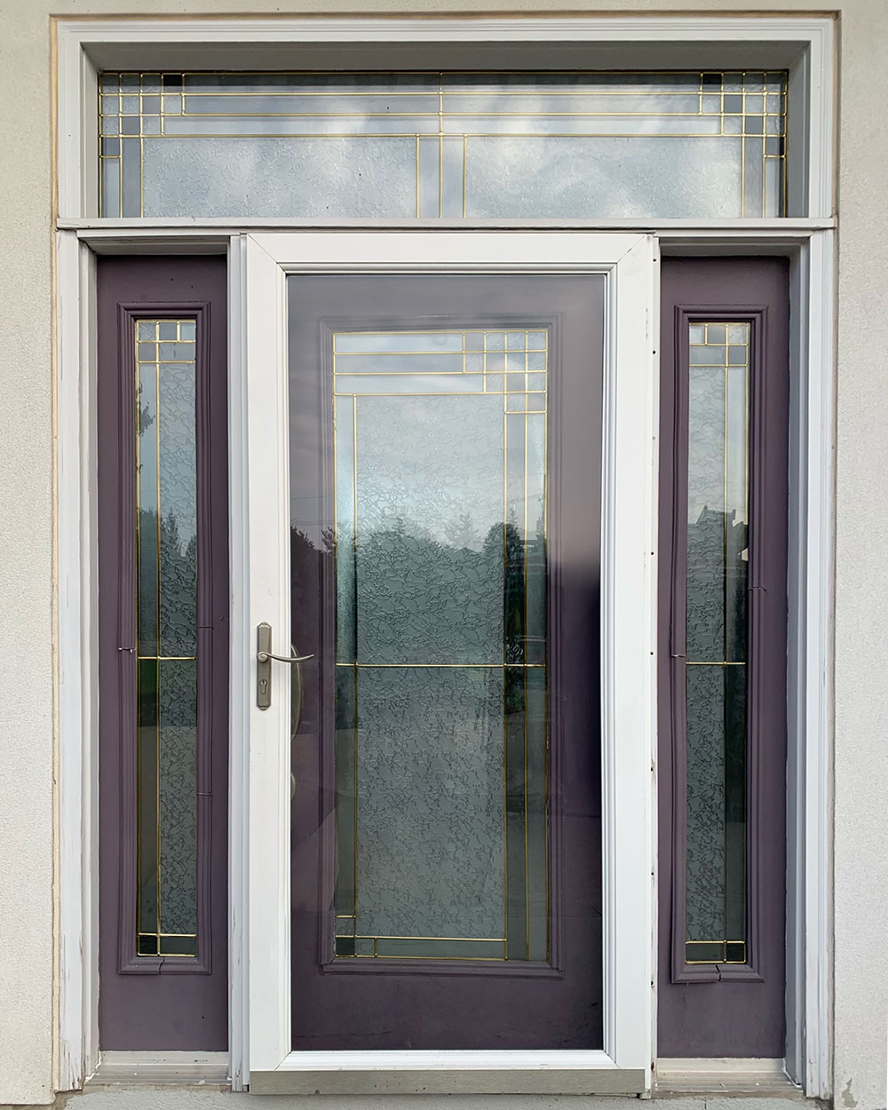 An older looking plum colored entry door and sidelites with a white storm door before getting a new entry door