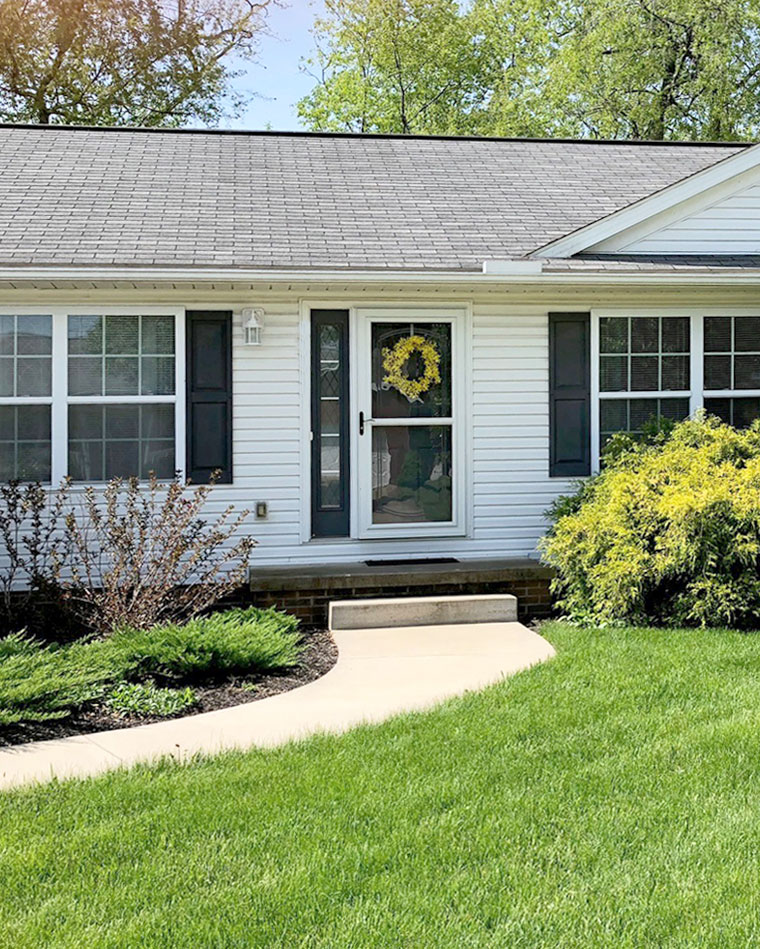 Outside view of the front of a white ranch home with an older looking roof before getting a new roof and entry door