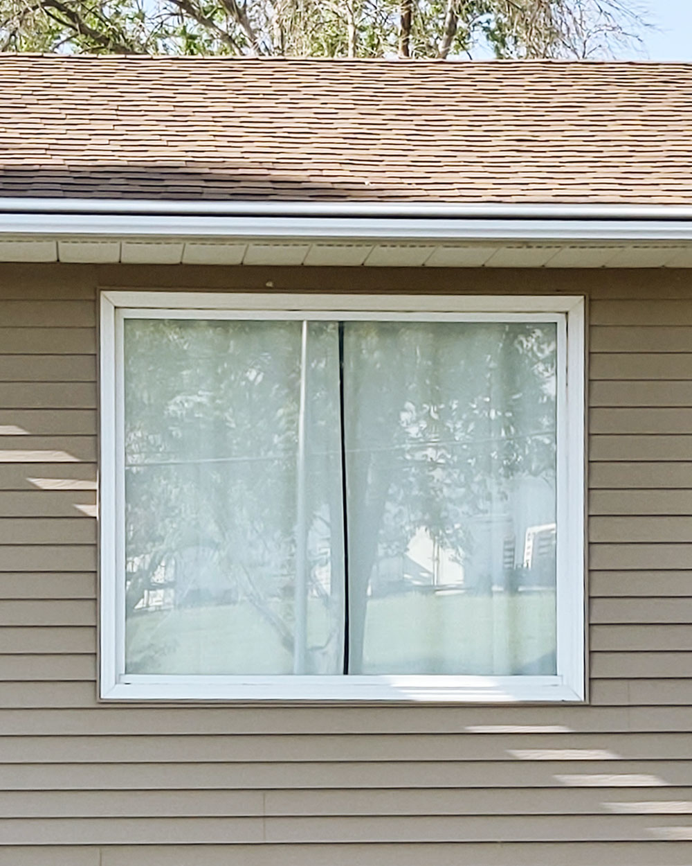 Exterior view of a white window before it got replaced with a new window