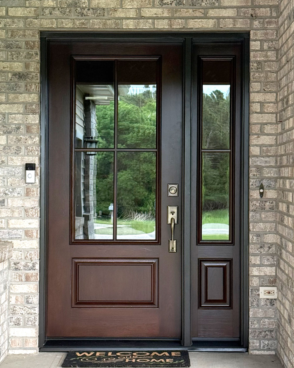 Exterior view of a ProVia® Signet® Cherry 440-1P Entry Door and 140 Sidelite with Simulated Divided Lites in Hazelnut on a light colored brick home